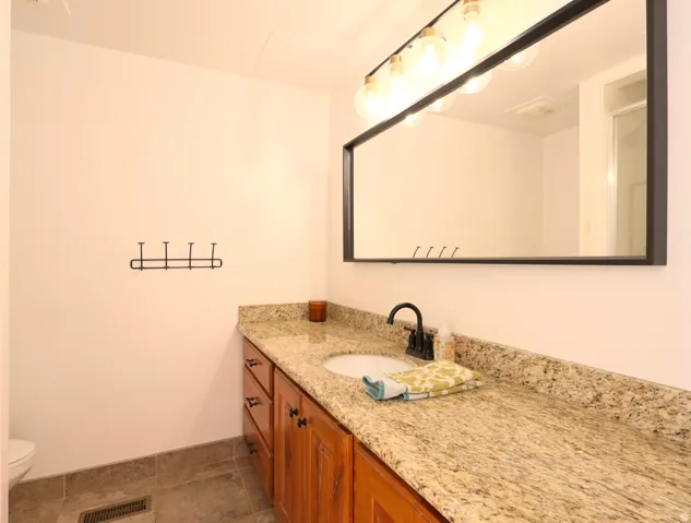 Vanity featuring a light-toned countertop, wood-finish cabinetry, and a black-framed mirror