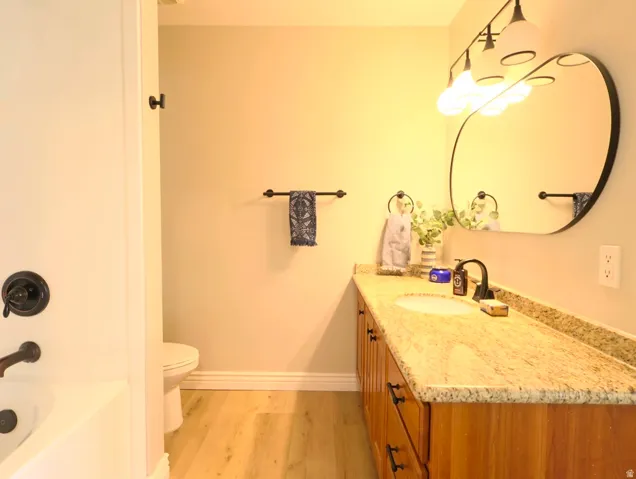 Bathroom featuring a wood-finish vanity with a granite countertop, undermount sink, and dark bronze faucet