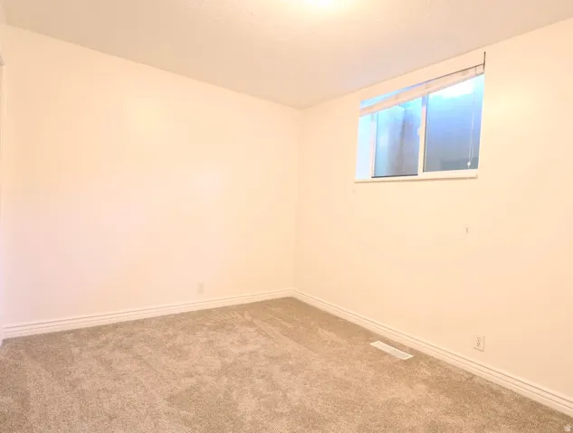 Carpeted room with a single window, white walls, and baseboard trim
