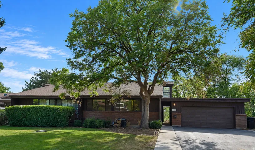 Mid-century modern residence featuring a brick facade, integrated single-car garage, and a lush front lawn
