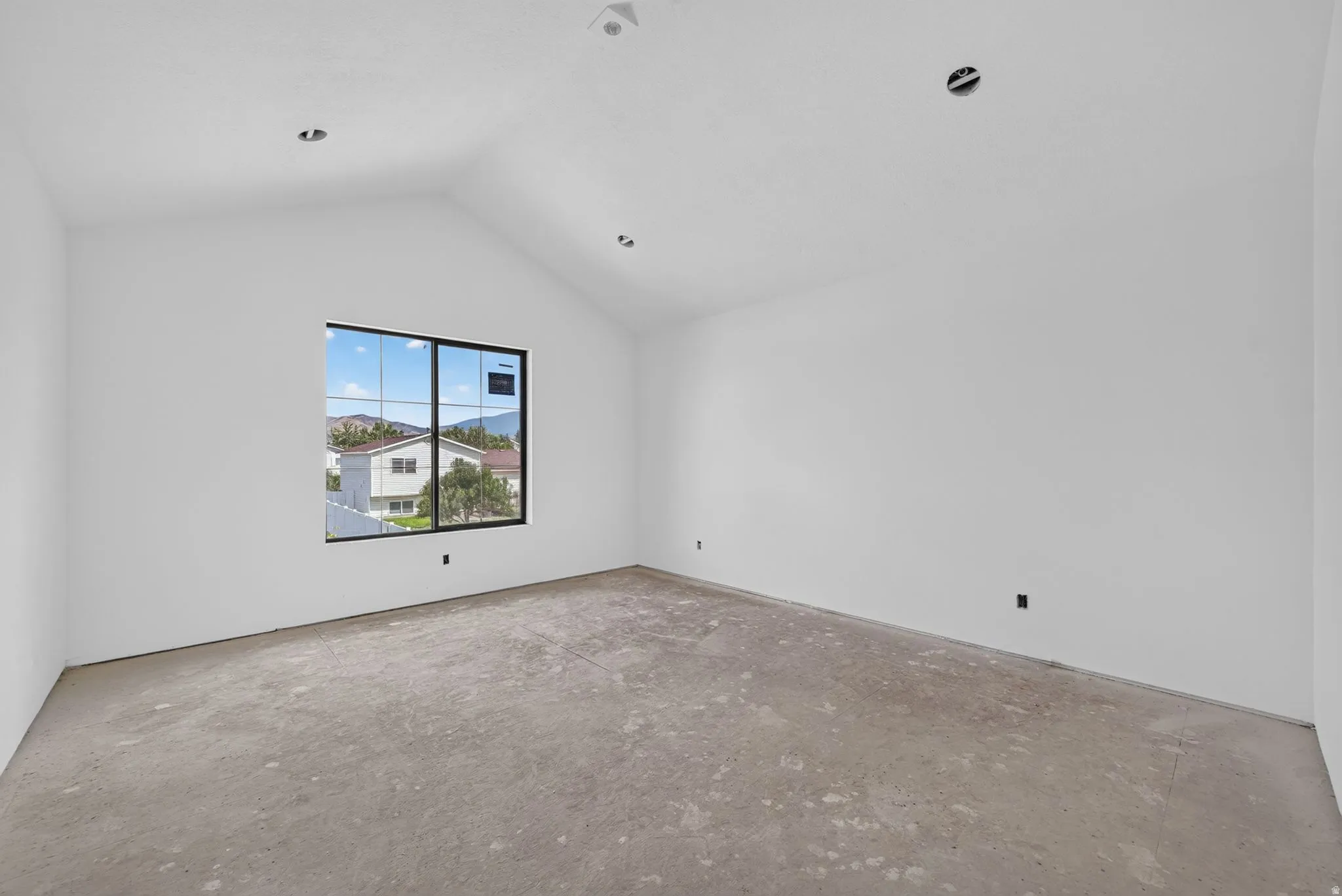 Vaulted ceiling, recessed lighting, expansive window with black trim, concrete flooring, neutral wall finishes