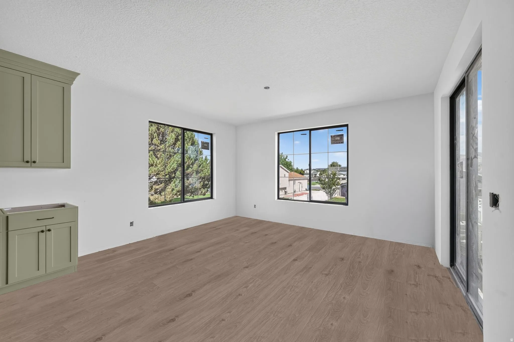 Wood-finish flooring, built-in cabinetry, large windows, and a sliding glass door