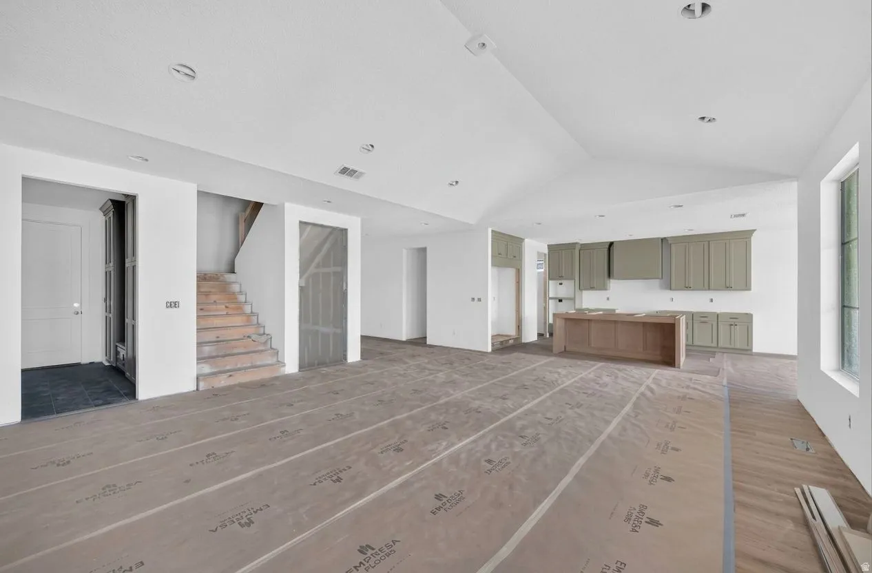Spacious interior with vaulted ceilings, recessed lighting, a modern kitchen island, and sage green cabinetry