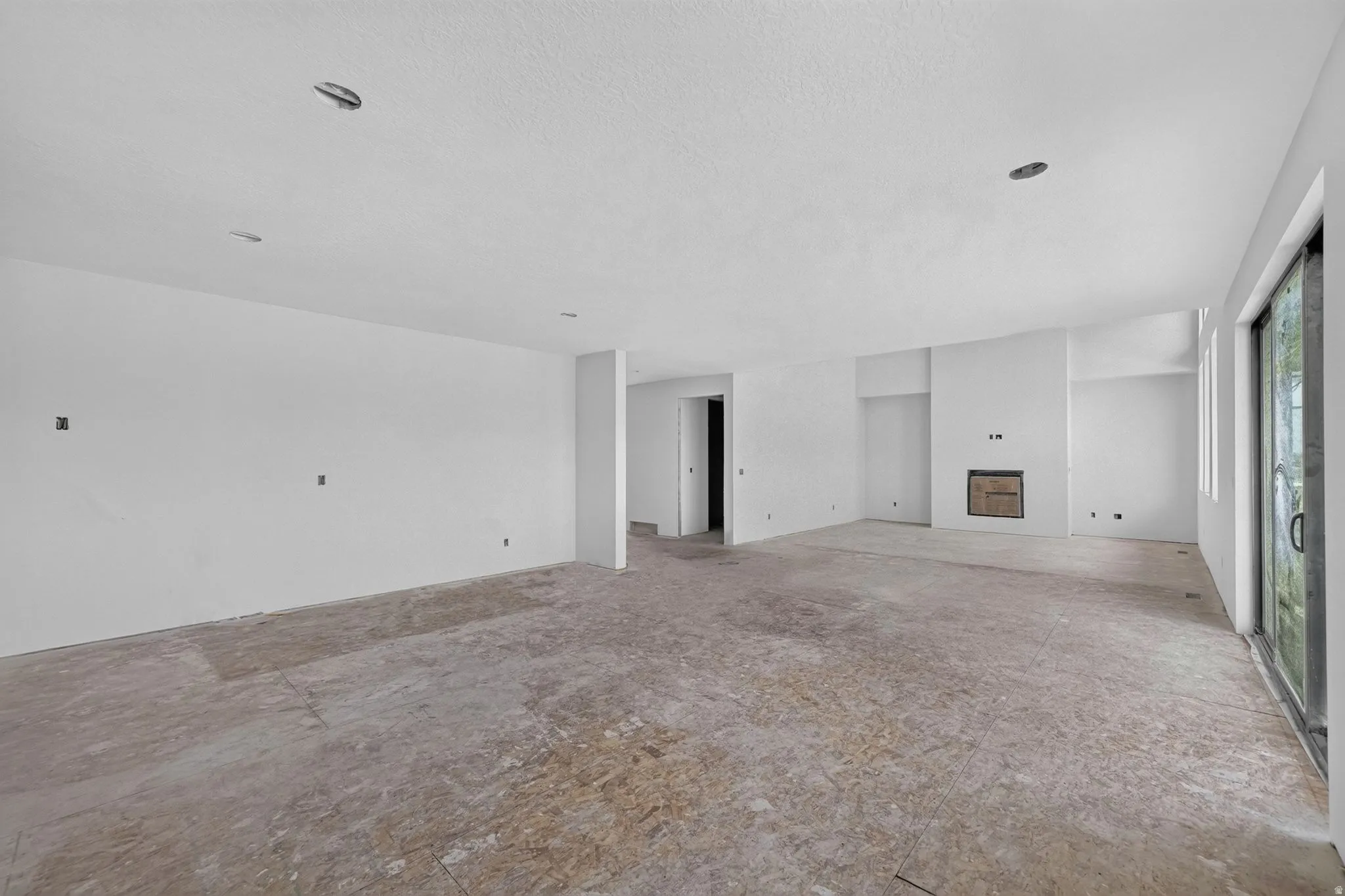 Spacious room with a built-in fireplace, recessed lighting, and large sliding glass doors