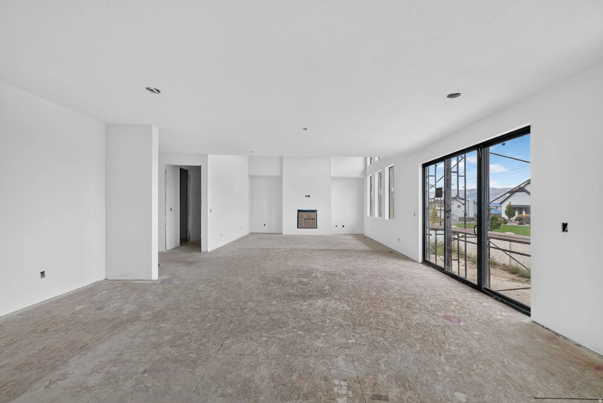 Expansive open-concept space featuring a built-in fireplace, multiple windows, and a large sliding glass door