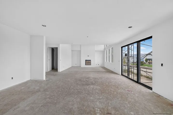 Expansive open-concept space featuring a built-in fireplace, multiple windows, and a large sliding glass door