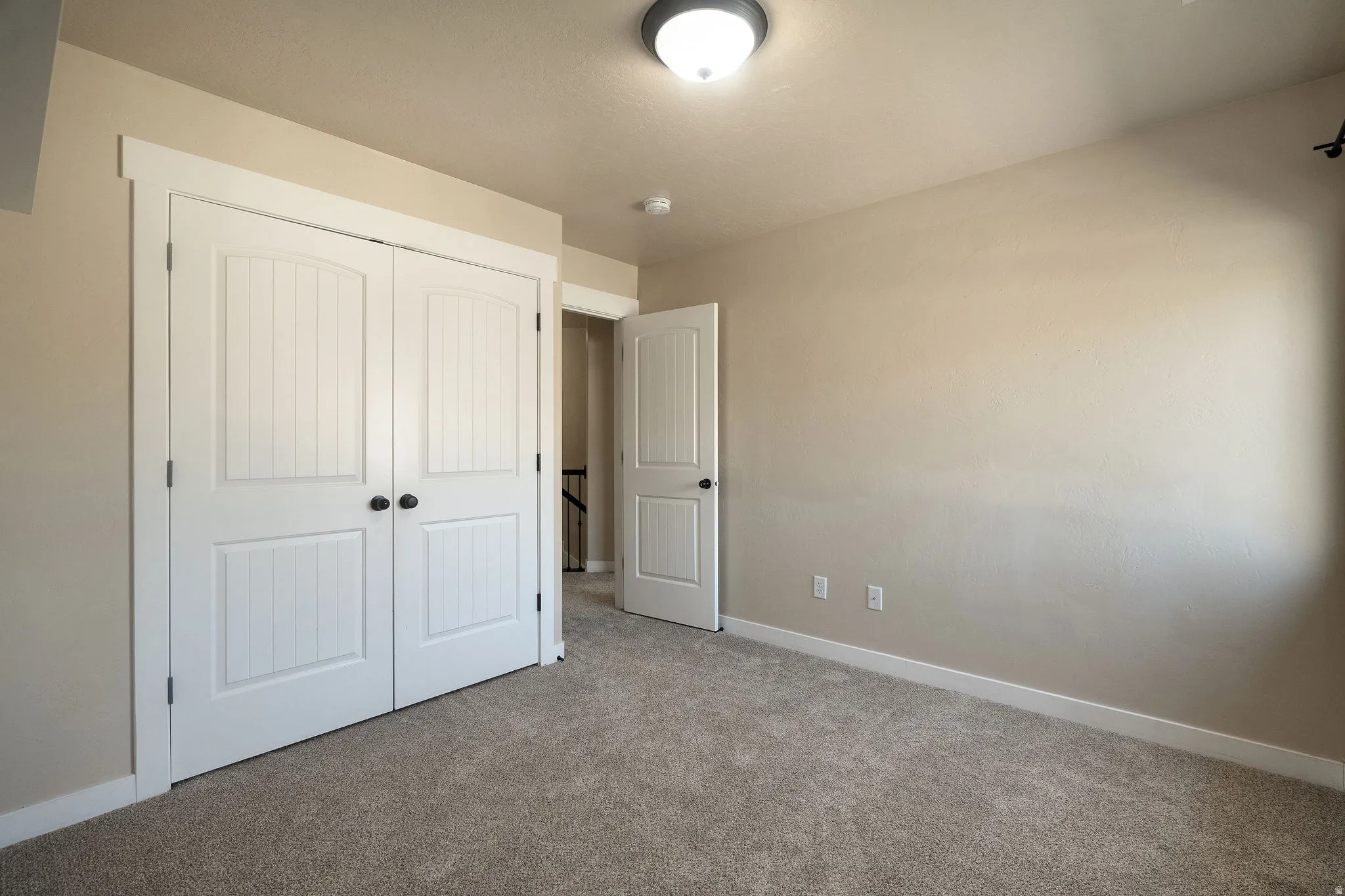 Room featuring neutral wall tones, plush gray carpet, white baseboards, and a semi-flush mount ceiling light