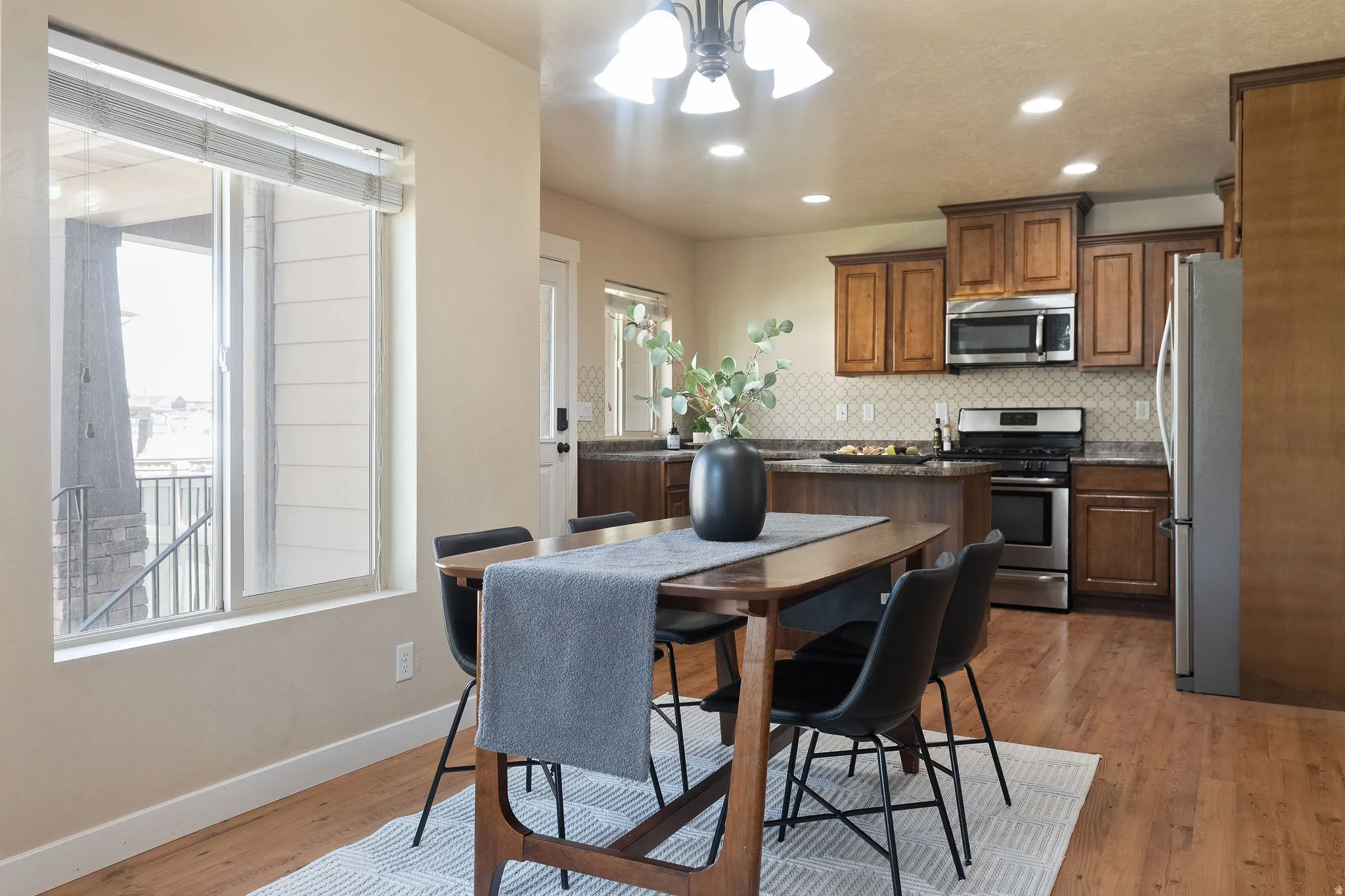 Open-concept dining area with wood-finish flooring, a contemporary chandelier, and recessed lighting