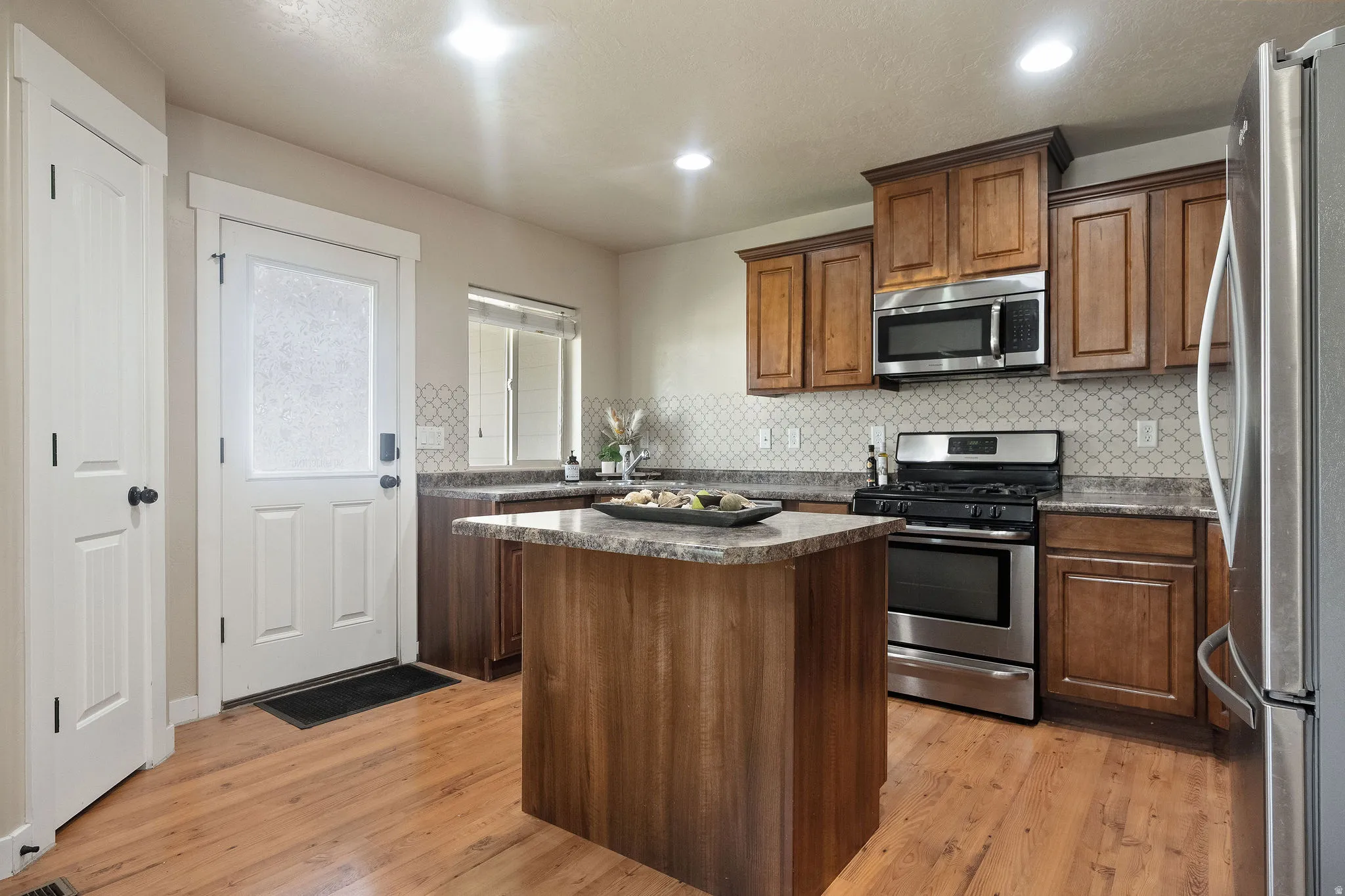 Kitchen featuring a central island, wood-finish flooring, and a patterned tile backsplash