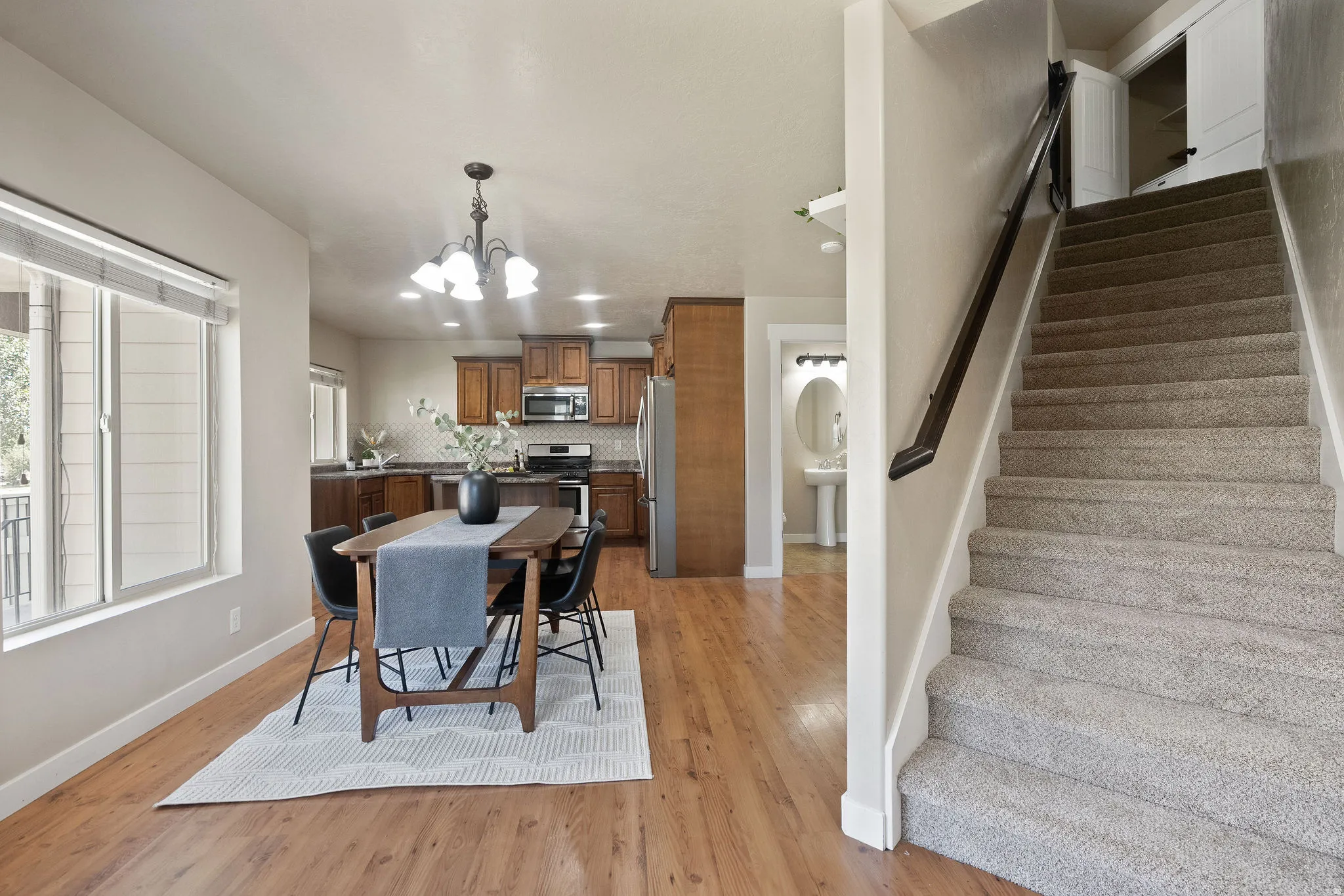 Open-concept main level featuring wood-finish flooring, a kitchen with dark wood cabinetry and stainless steel appliances, and a dining area with a chandelier