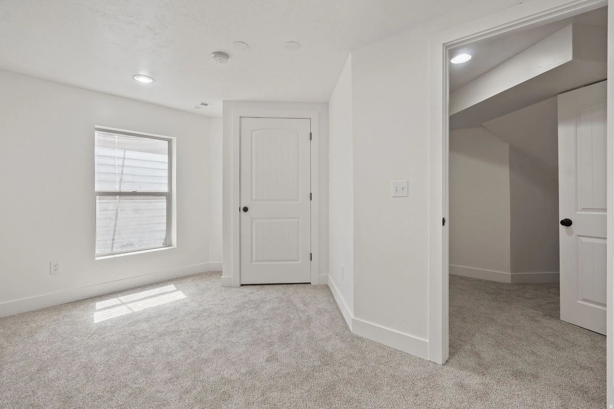 Carpeted room with a window featuring horizontal blinds, recessed lighting, and white trim