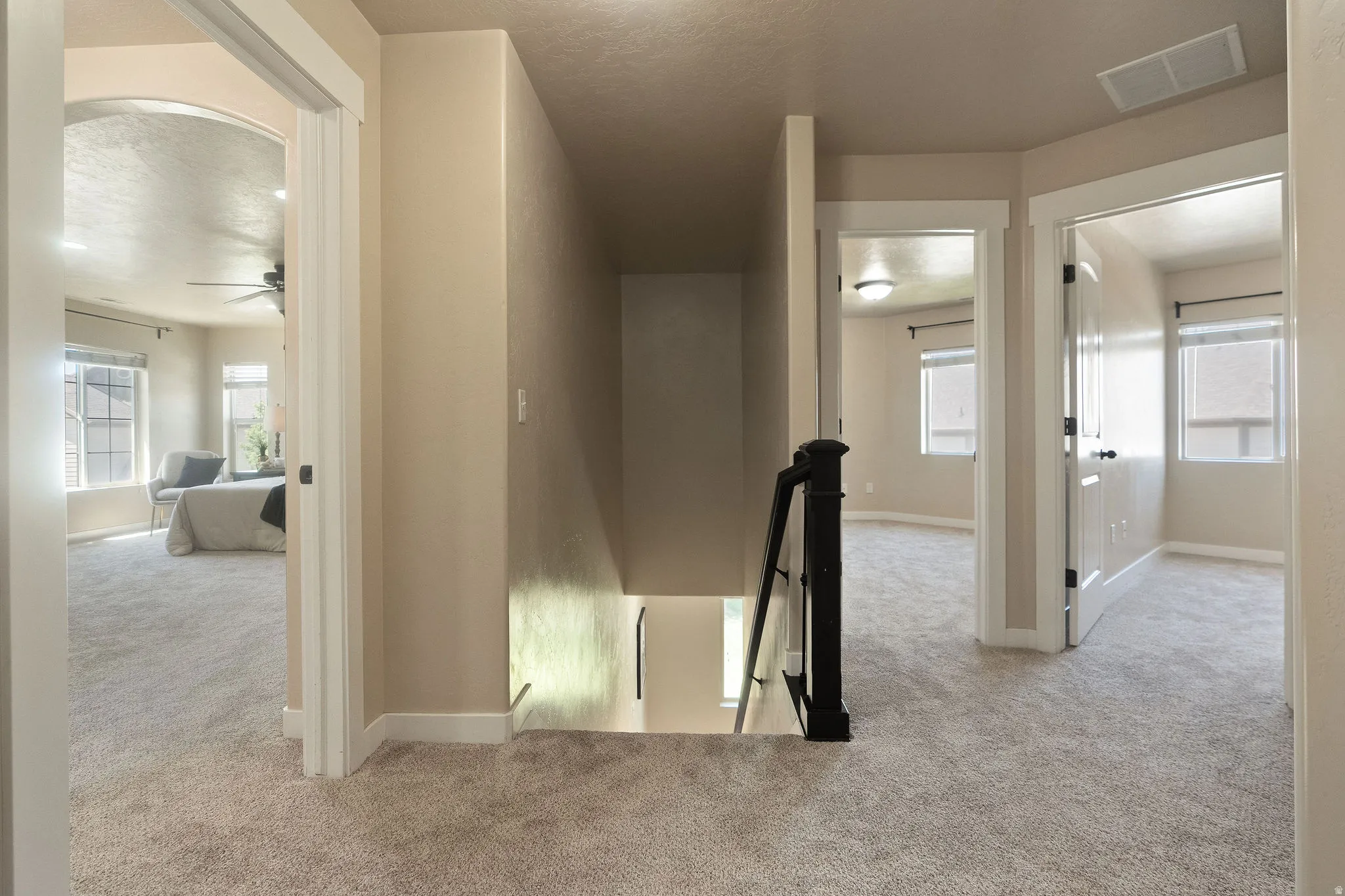 Upper-level landing featuring neutral carpeting, white trim, and doors with dark hardware