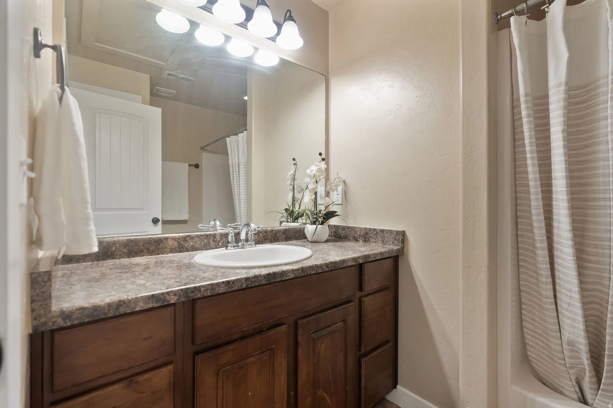 Bathroom vanity with a round undermount sink, dual-handle chrome faucet, and a large wall-mounted mirror