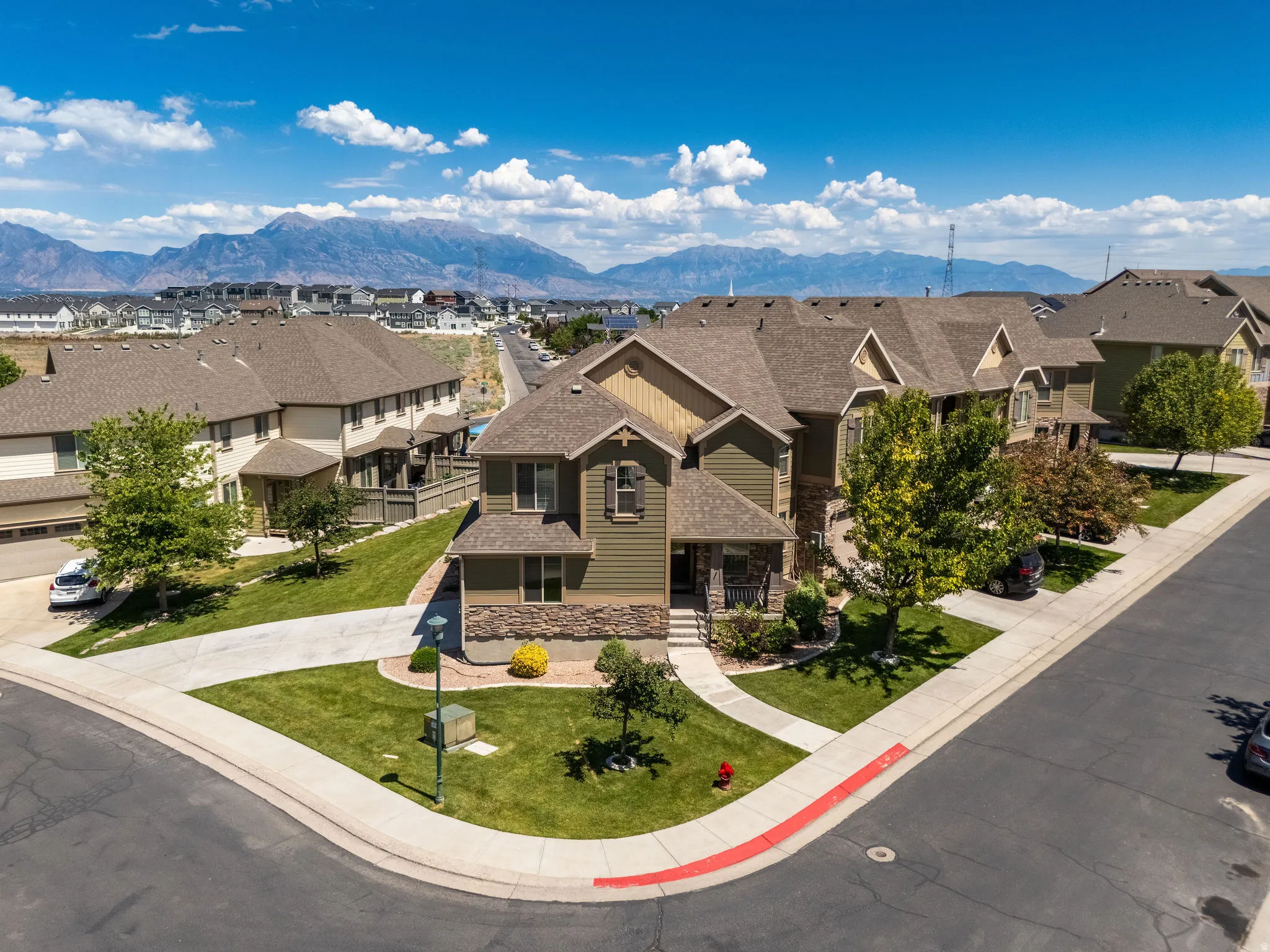 Residential property featuring a stone and siding exterior, a paved driveway, and established landscaping