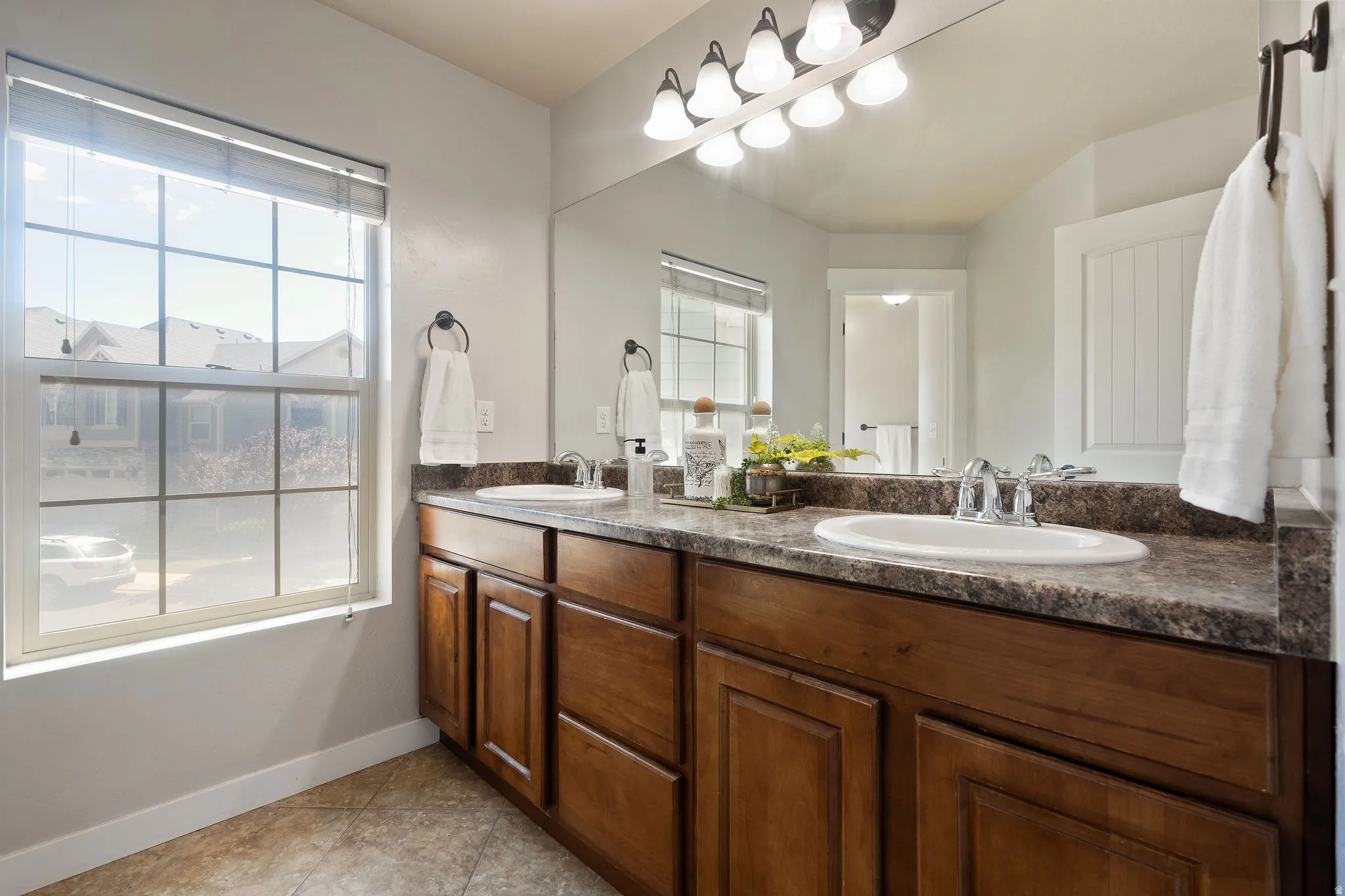 Dual vanity featuring wood-finish cabinetry, integrated sinks, and patterned countertops