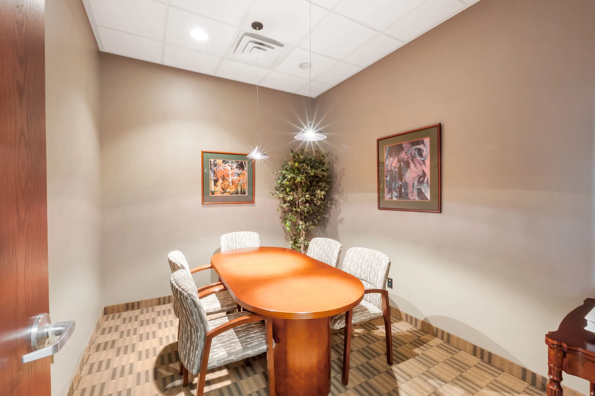 Compact room featuring recessed lighting, a drop ceiling, wood-finish door, and patterned floor tiles
