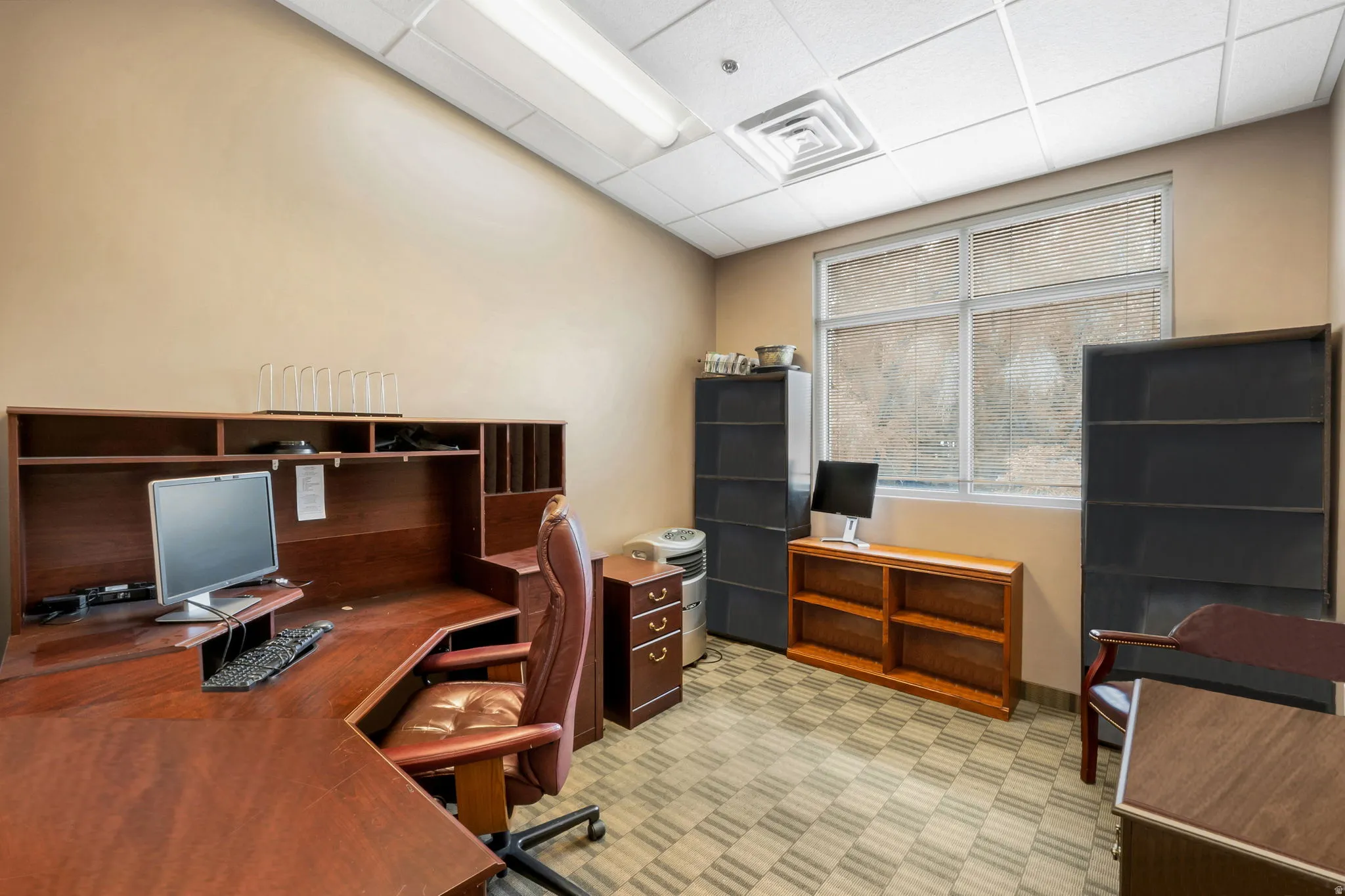 Office space featuring a large corner desk with hutch storage, window with blinds, and recessed lighting