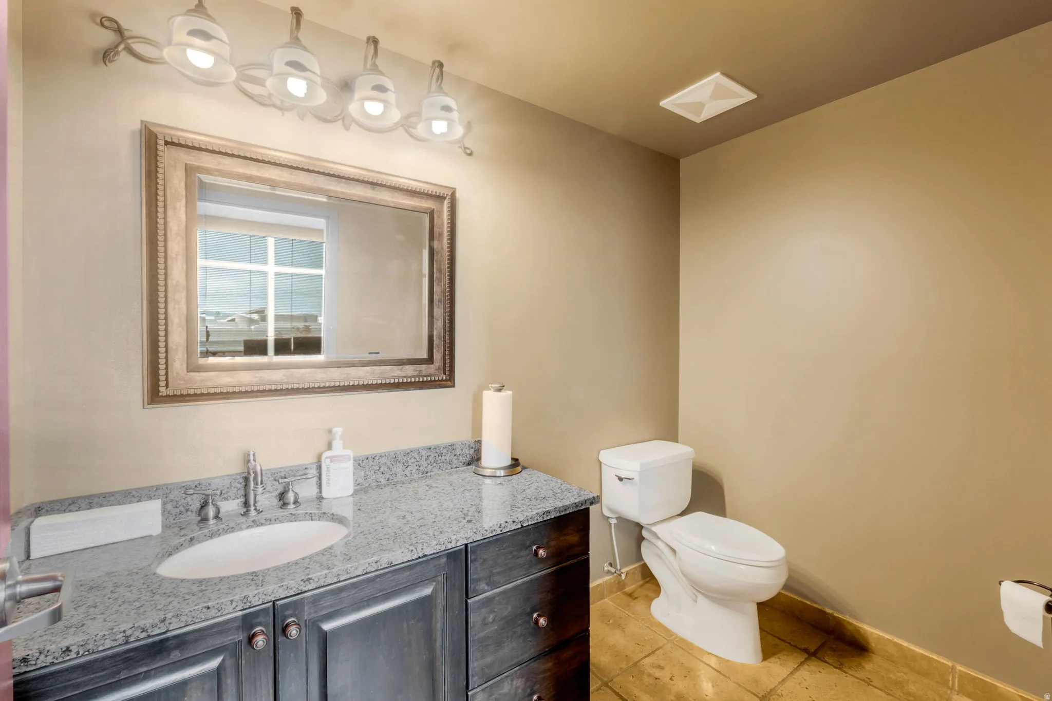 Bathroom featuring a dark wood-finish vanity with a granite countertop and an undermount sink