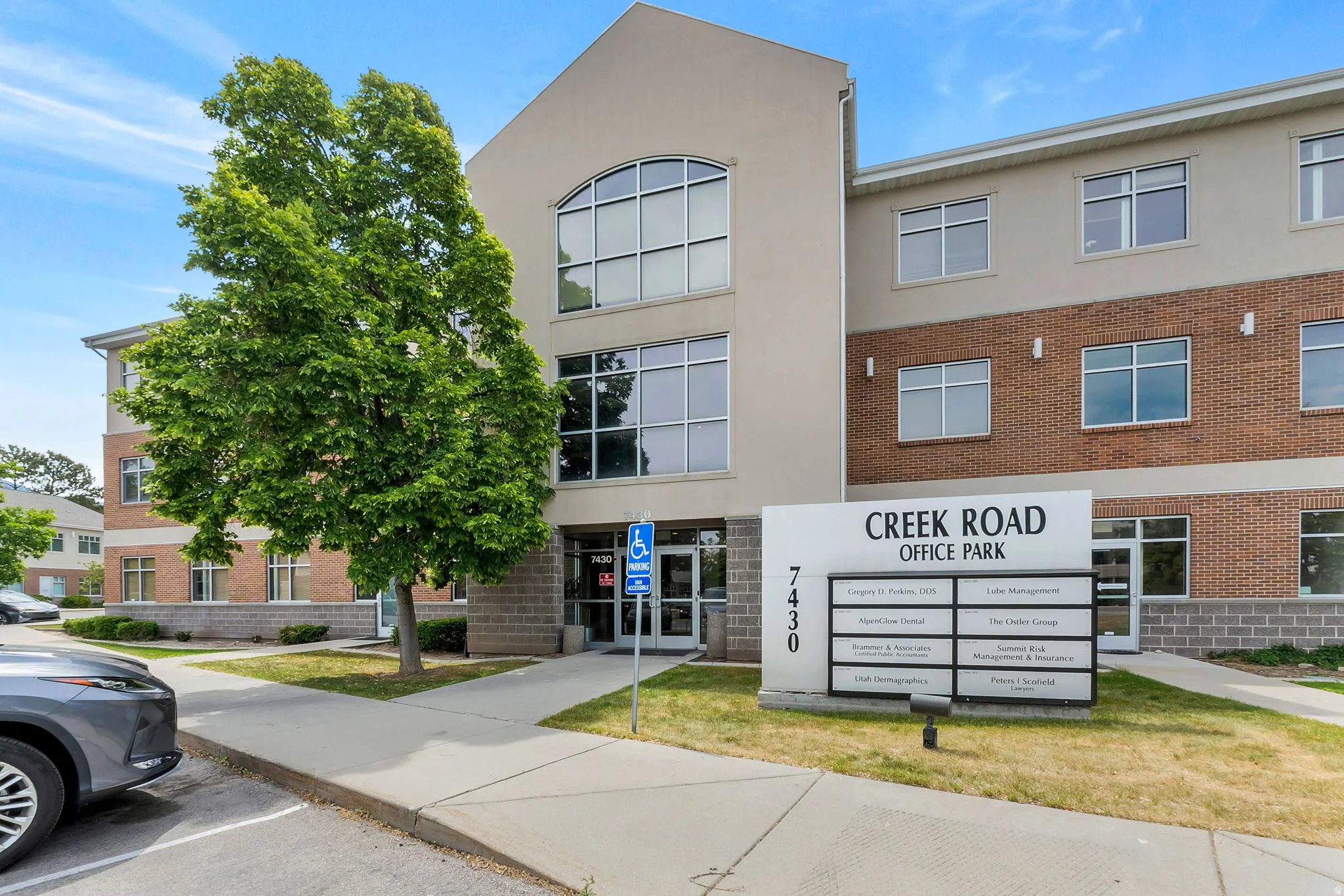 Multi-story office building featuring a light stucco facade and brick accents