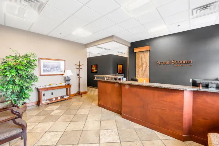 Commercial reception area featuring a wood-finish desk with a stone countertop, an accent wall with stone detailing, and a patterned tile floor