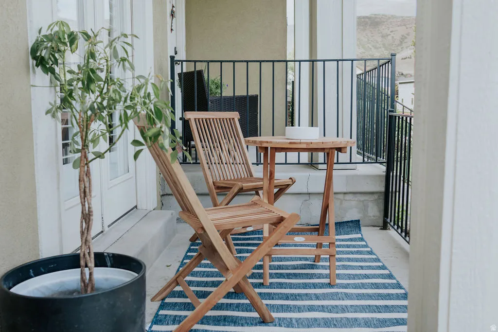 Outdoor balcony featuring a striped rug and black metal railings