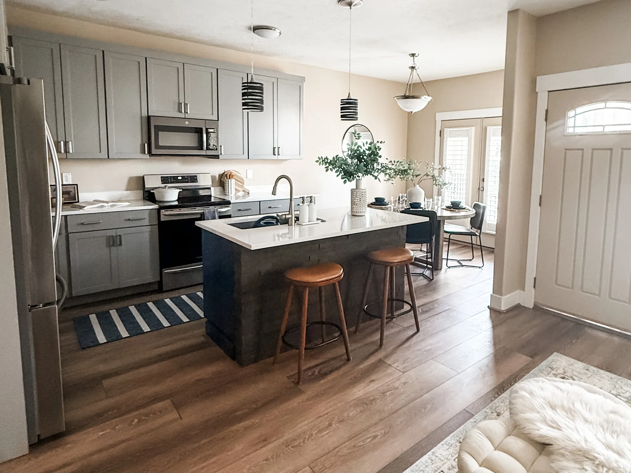 Open-concept kitchen featuring wood-finish flooring, gray shaker-style cabinetry, and stainless steel appliances