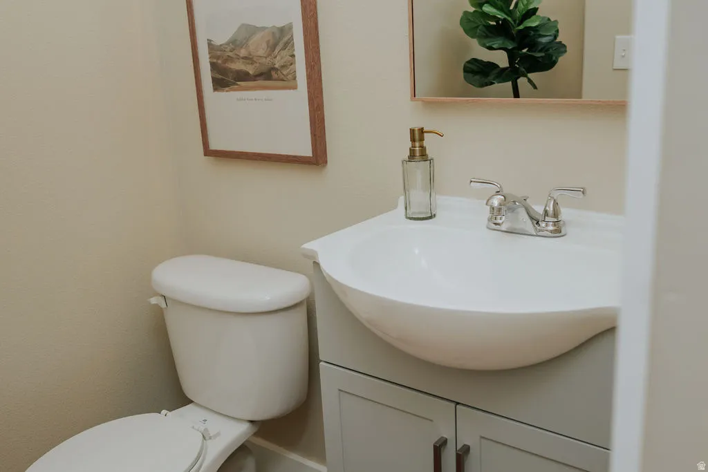 White porcelain toilet with a light grey vanity featuring a built-in sink and chrome faucet