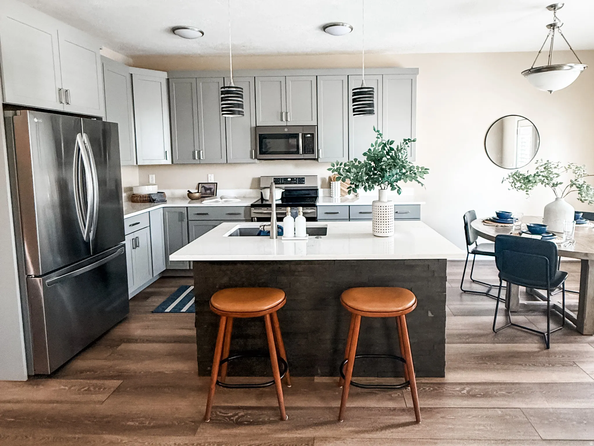 Open-concept kitchen featuring wood-finish flooring, two-tone cabinetry, and a central island with an integrated sink