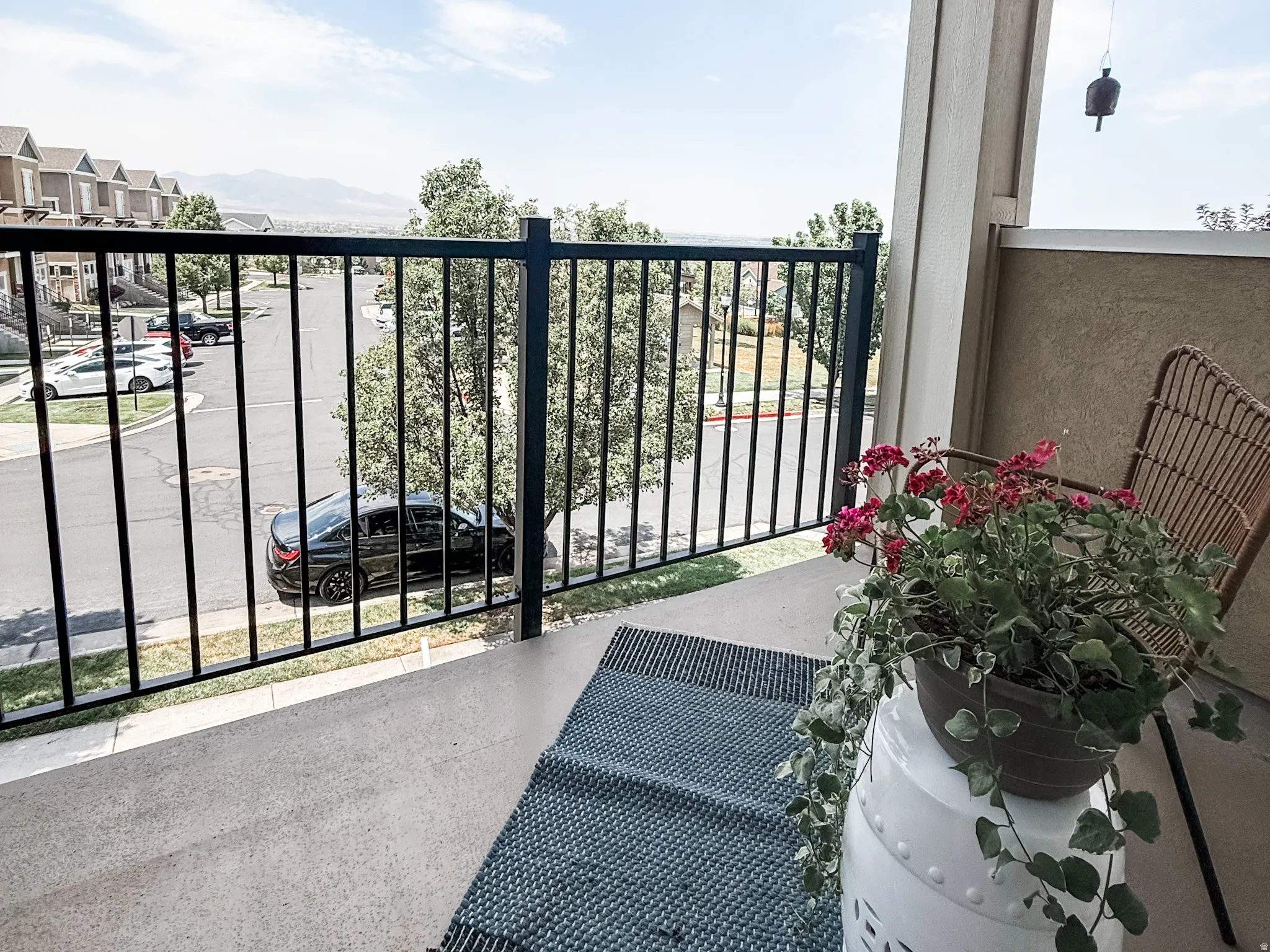 Private balcony with a dark metal railing and concrete flooring
