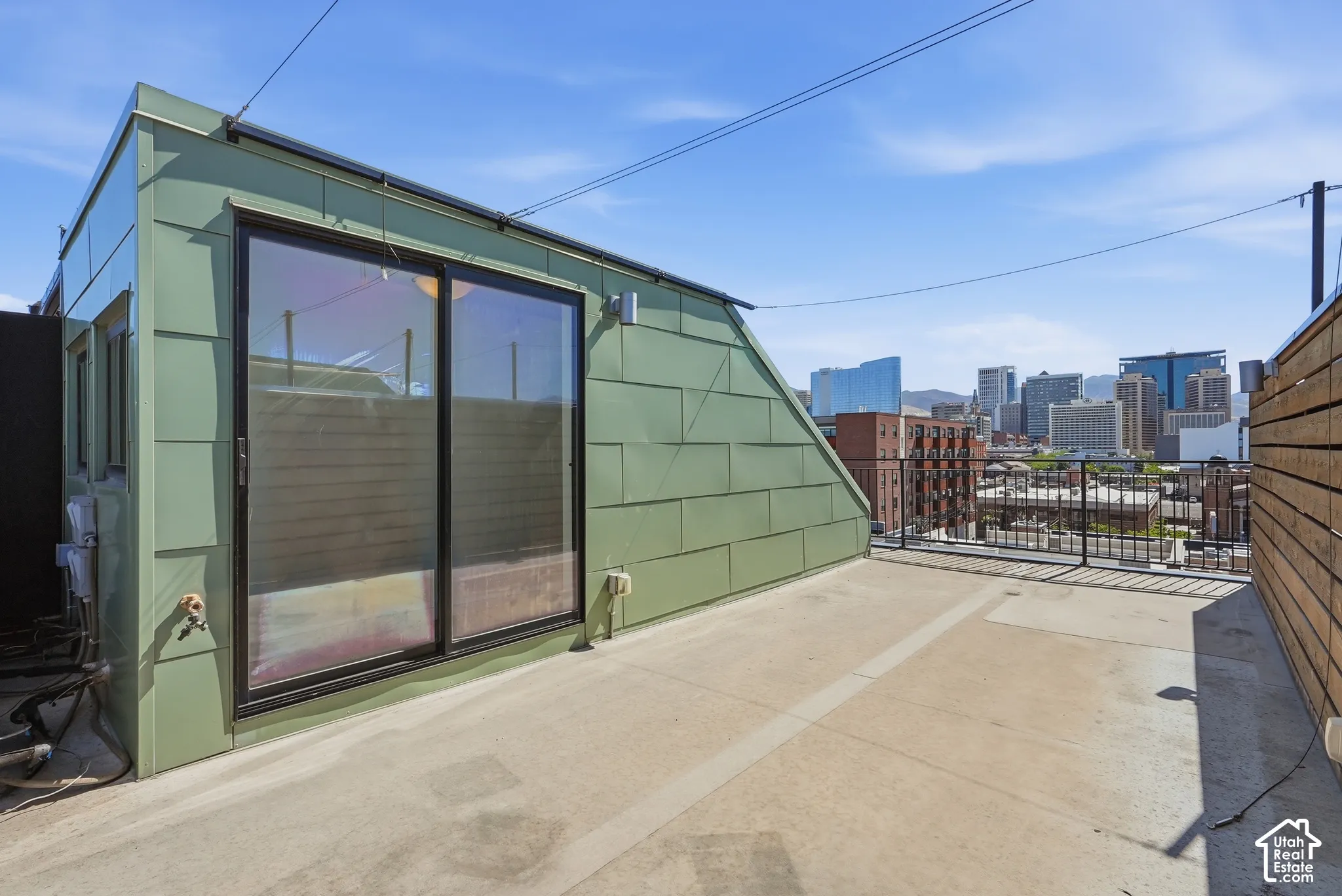 Expansive rooftop patio with concrete surfacing and a metal railing