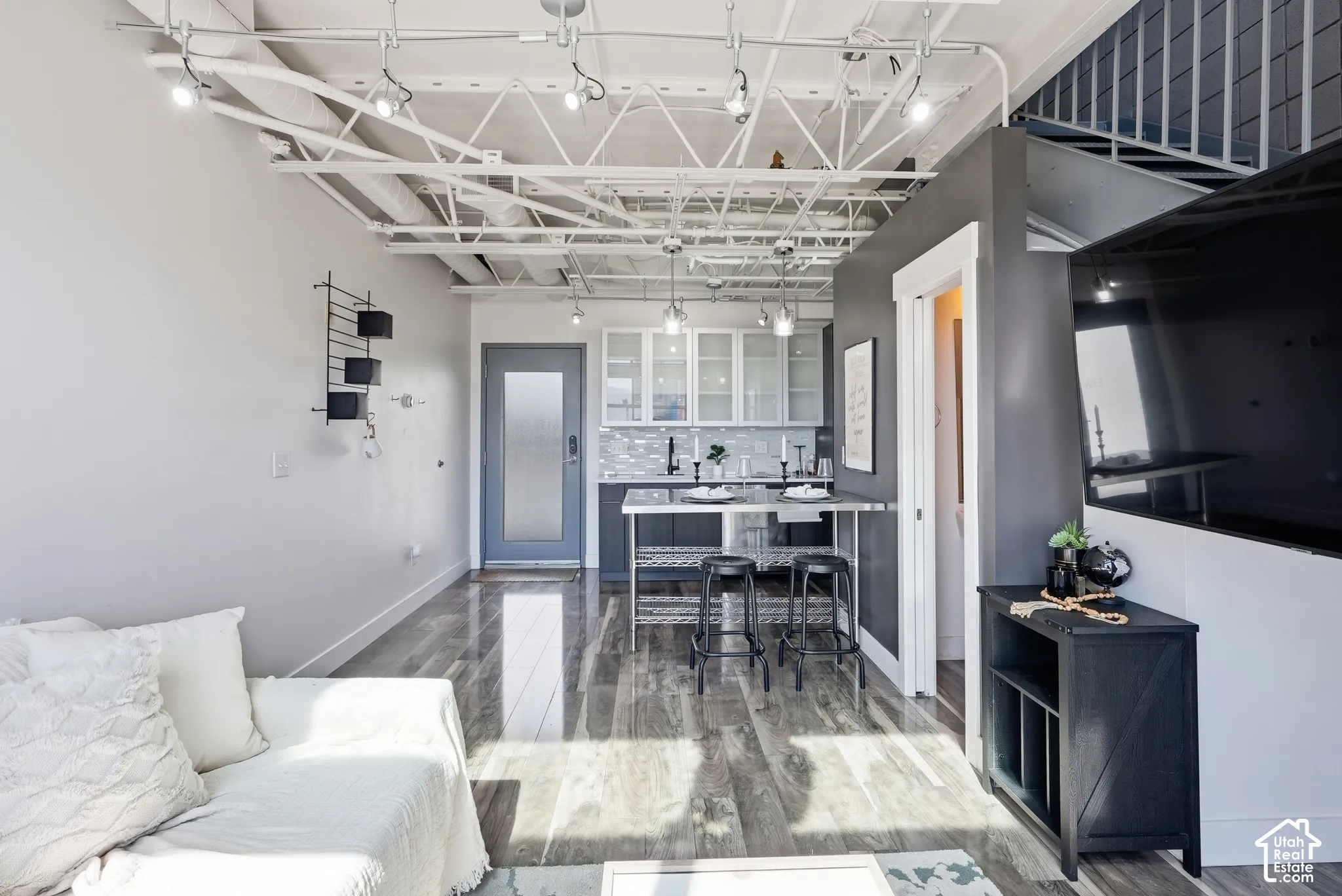 Open-concept living space with exposed ceiling trusses and track lighting