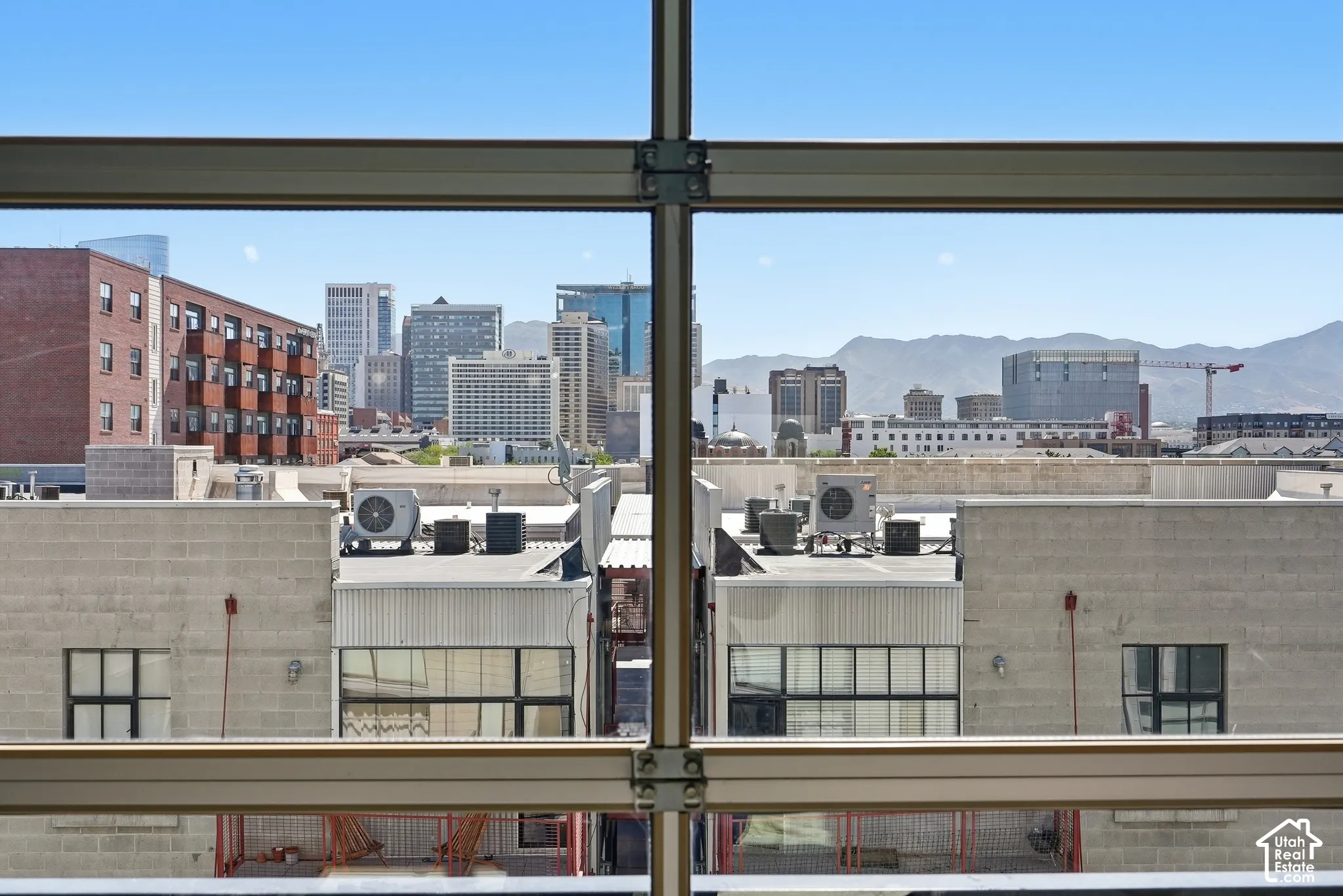Expansive city skyline and distant mountain range framed by structural window elements