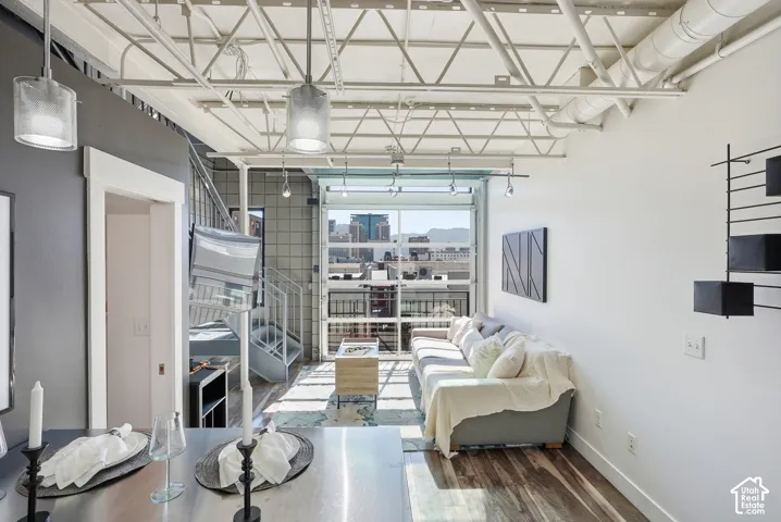 Loft-style living area featuring exposed ceiling trusses, a full-lite glass garage door, wood-finish flooring, and a spiral staircase