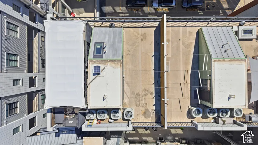 Rooftop area featuring multiple HVAC units, a large skylight, and a sloped metal roof section