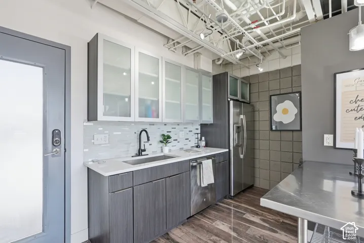 Contemporary kitchen featuring wood-finish flooring, white countertops, and a full suite of stainless steel appliances including a refrigerator and dishwasher