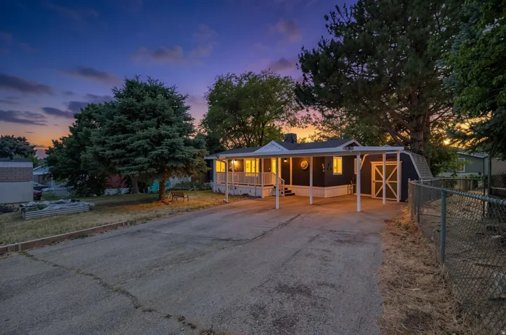 Exterior featuring a covered porch with white railings, a carport, and a detached shed with barn-style doors