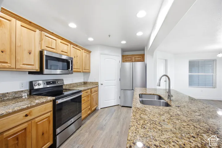 Kitchen featuring wood-finish cabinetry, stainless steel appliances, granite countertops, and wood-finish flooring