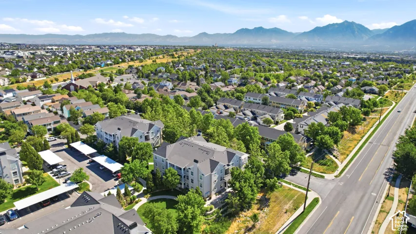 Expansive aerial panorama showcasing a residential community with abundant mature trees and mountainous terrain in the distance