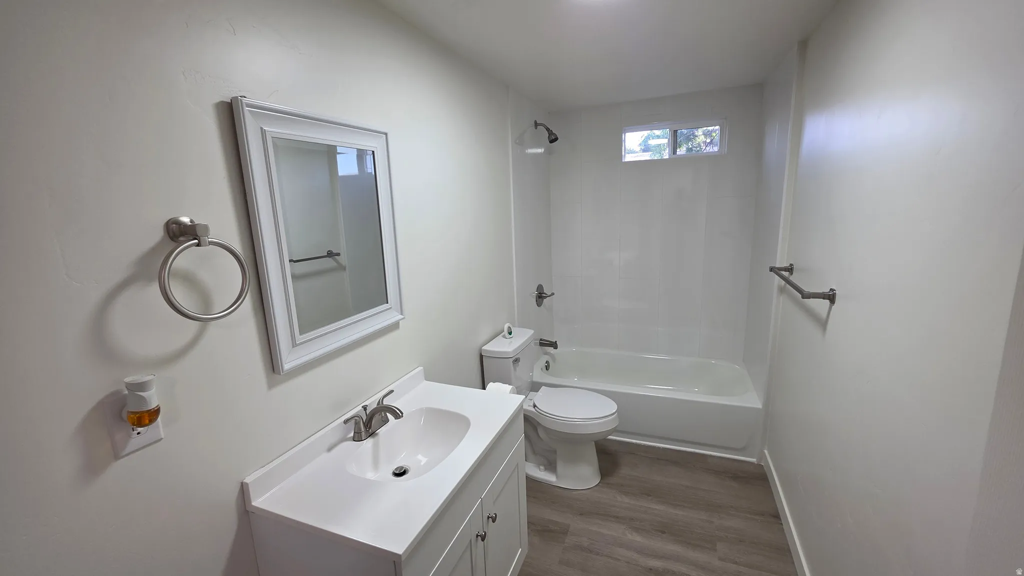 White vanity with integrated sink and brushed nickel faucet, framed mirror, and wood-finish flooring