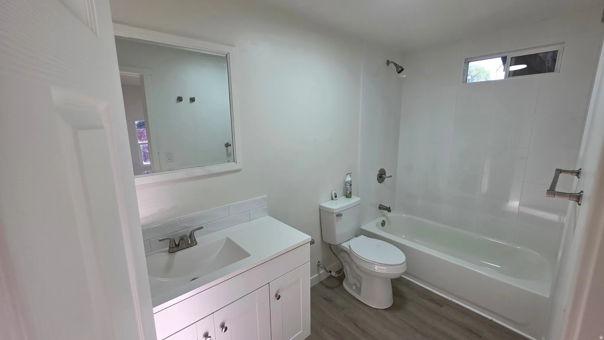 Bathroom featuring a white vanity with integrated sink, subway tile backsplash, and a framed mirror