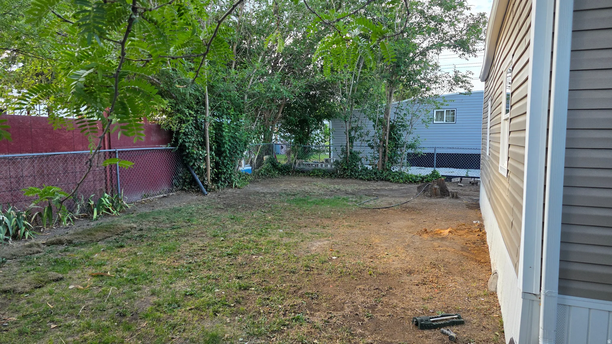 Side yard featuring beige vinyl siding, a visible foundation, and a chain link fence
