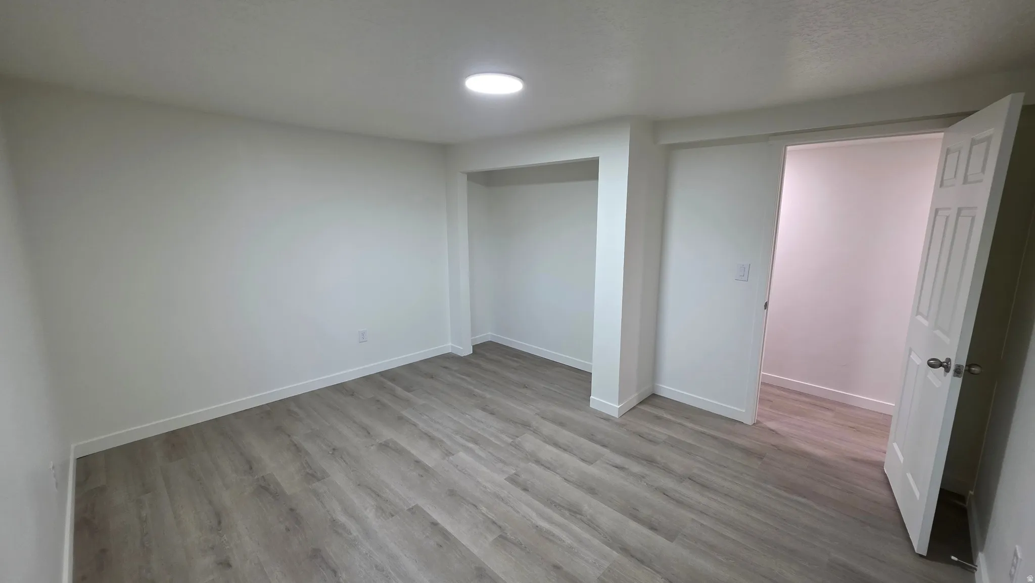 Spacious room featuring wood-finish flooring, recessed lighting, and a built-in closet area