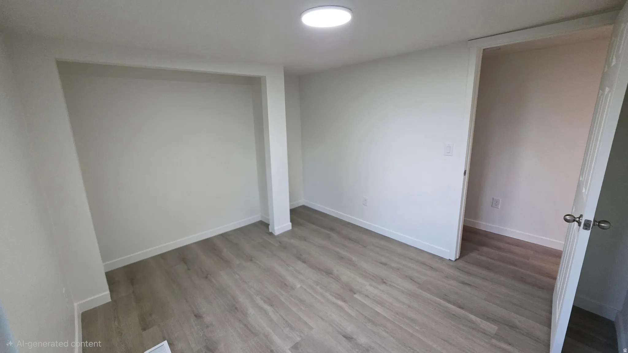 Room featuring light wood-finish flooring, white walls, built-in wall niche, and an overhead flush-mount light fixture