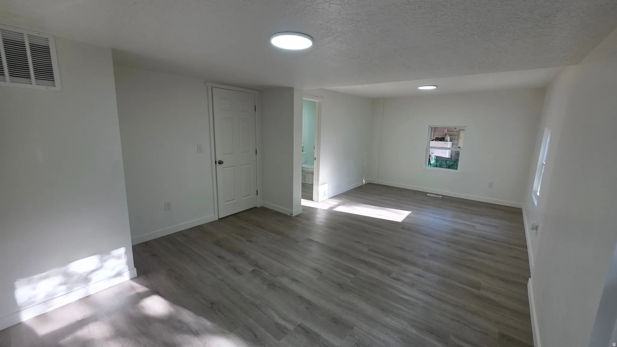 Spacious room featuring wood-finish flooring, white walls, and recessed lighting