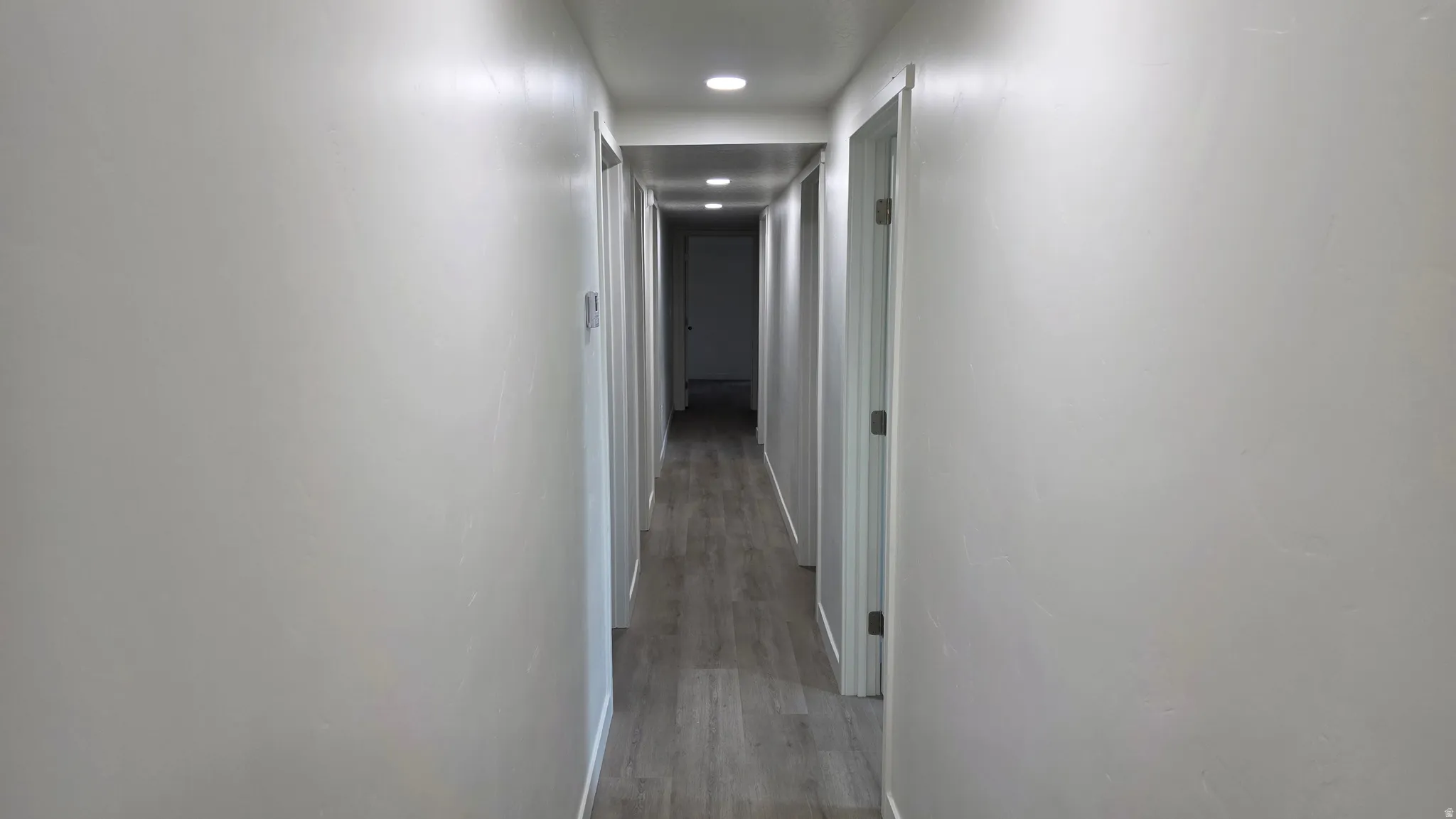 Hallway featuring light gray walls, recessed lighting, and wood-finish flooring