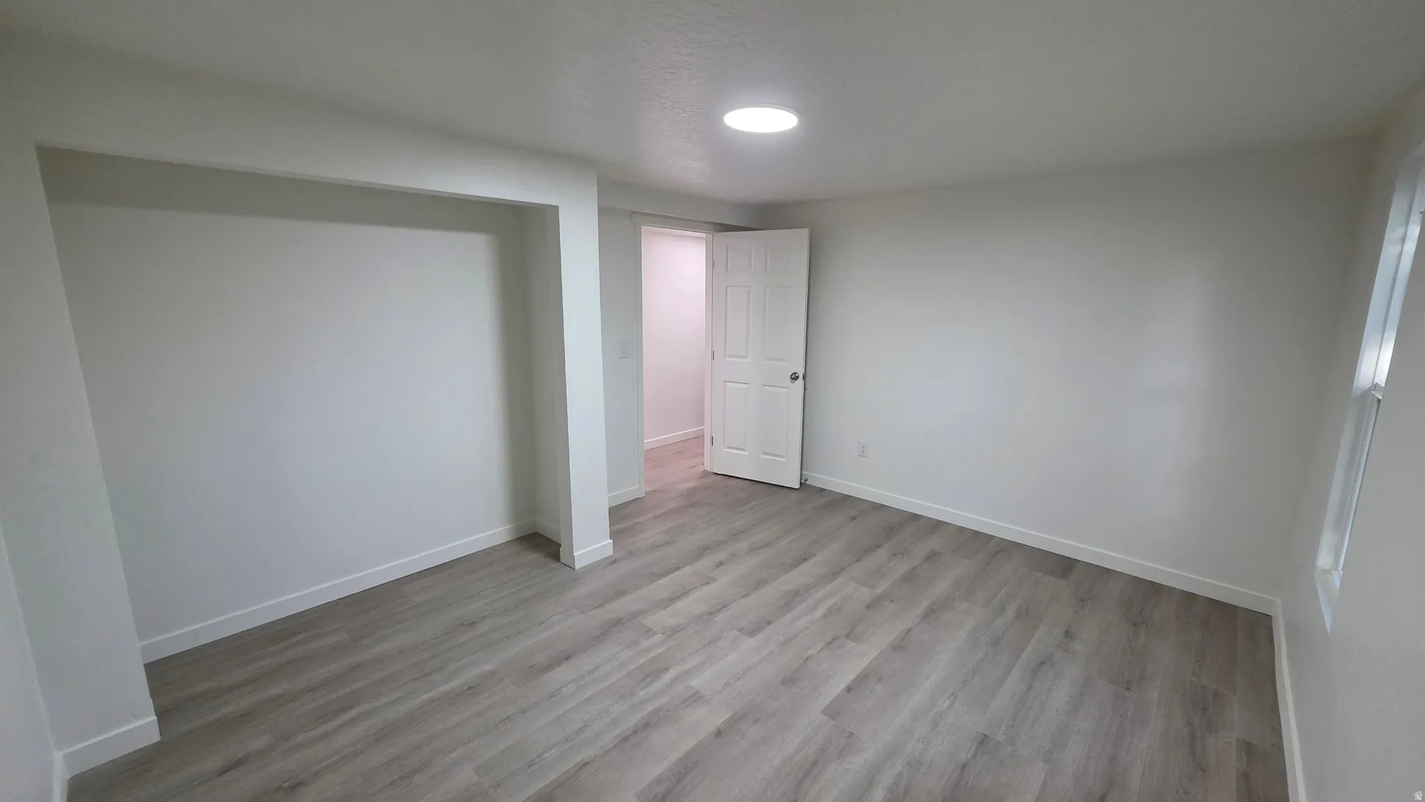 Spacious interior featuring wood-finish flooring, recessed lighting, a built-in wall niche, and white trim