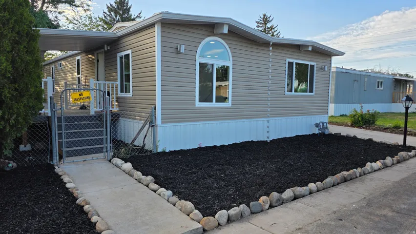 Tan siding exterior with white trim, featuring an arched window and multiple rectangular windows
