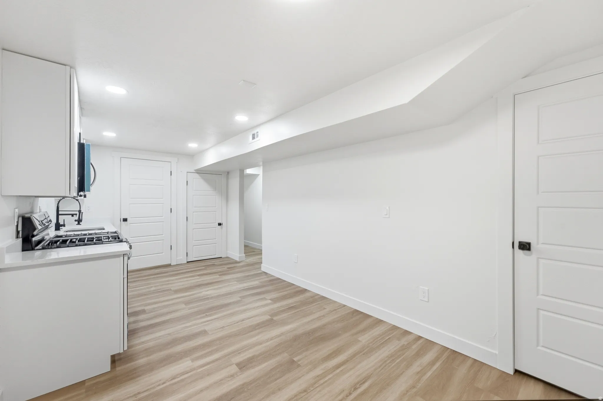Compact kitchen area featuring a built-in range, white shaker cabinetry, and a quartz-finish countertop