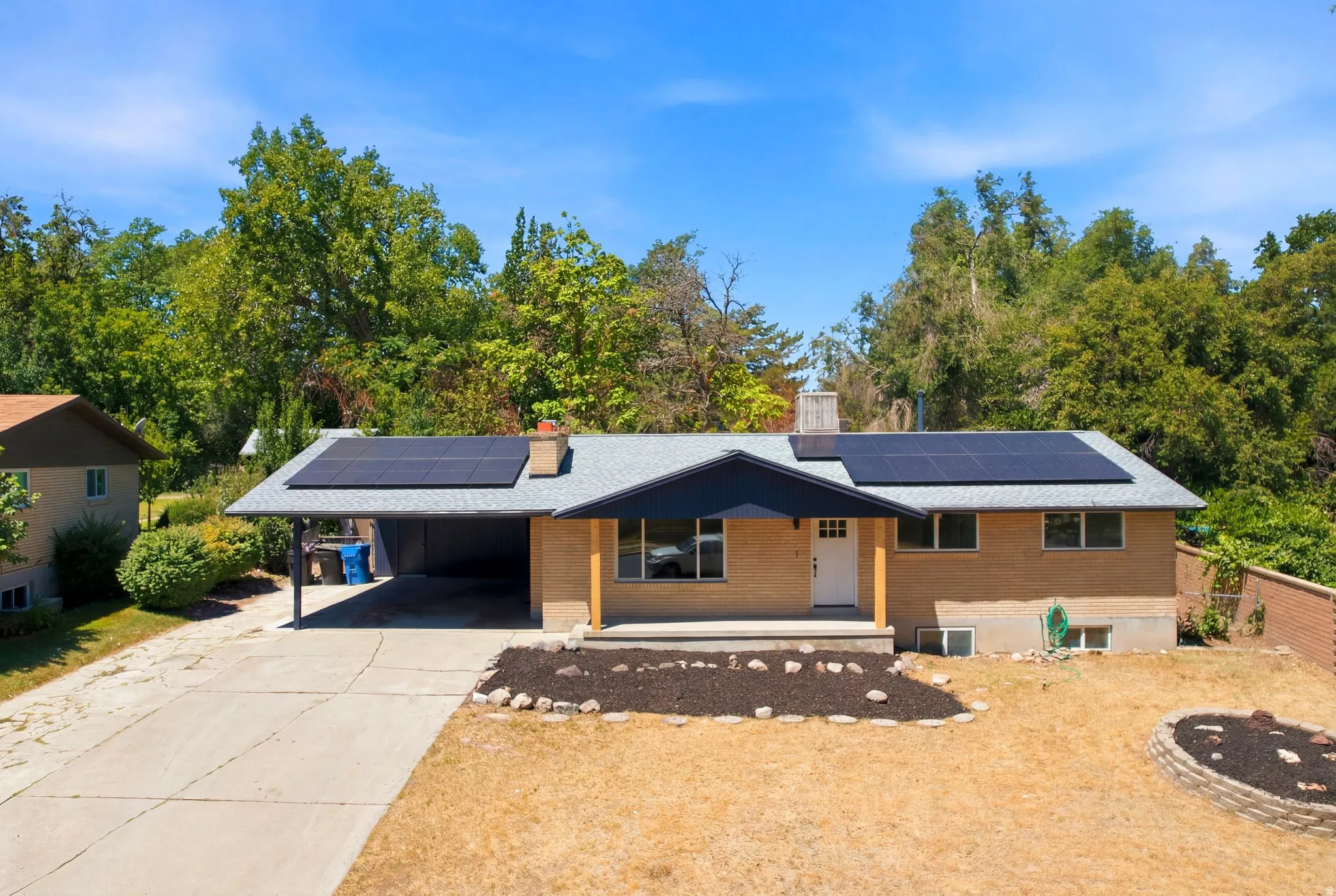 Brick exterior residence featuring solar panels, a carport, and a concrete driveway