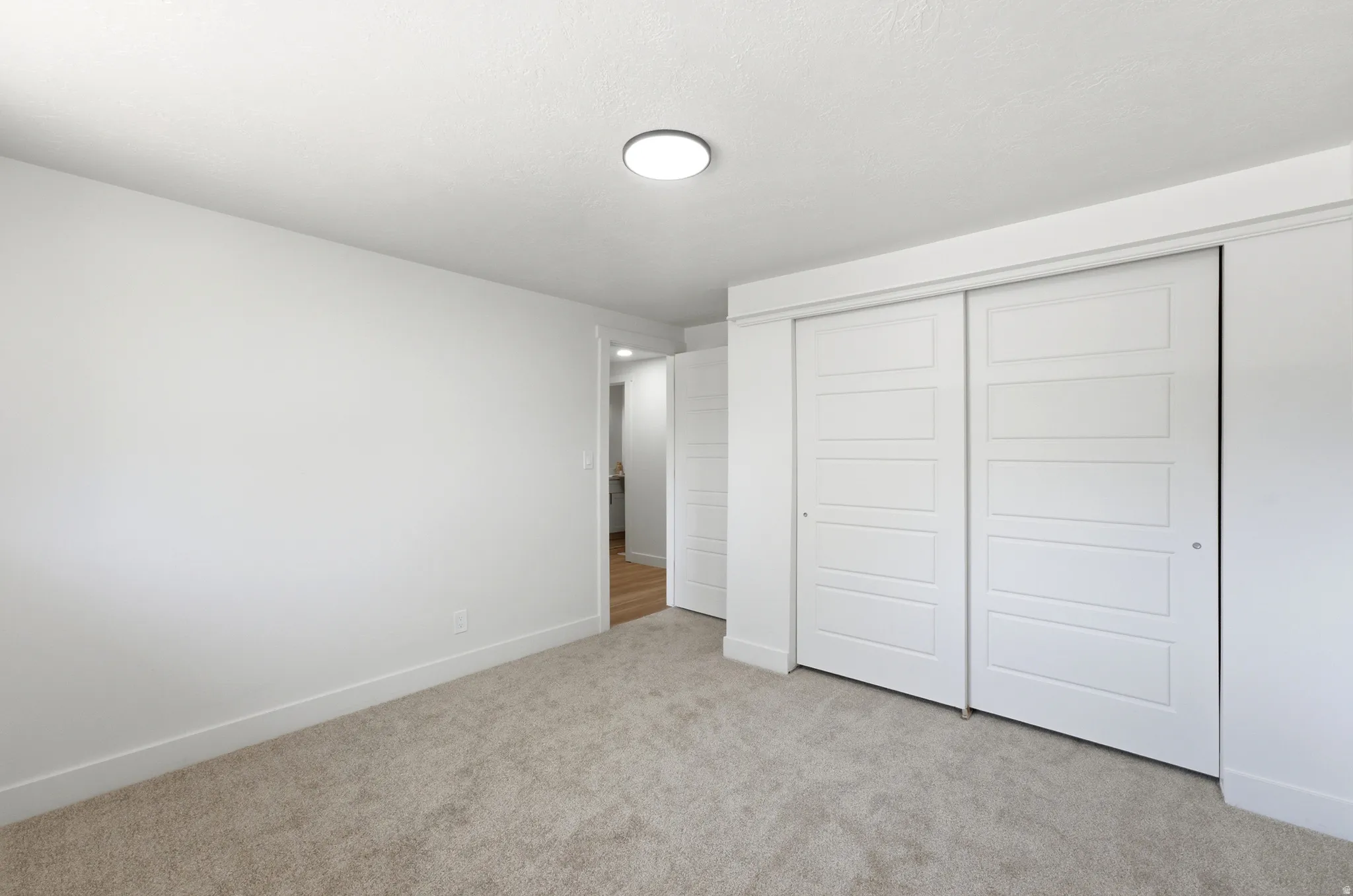 Room featuring plush carpet flooring, white painted walls, and a circular flush-mount ceiling light